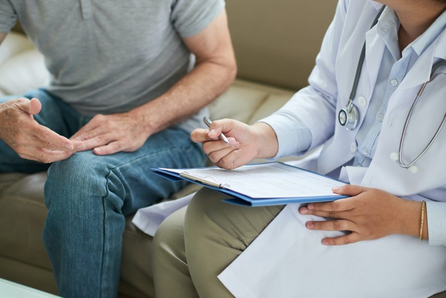 Doctor writing on clipboard during home visit