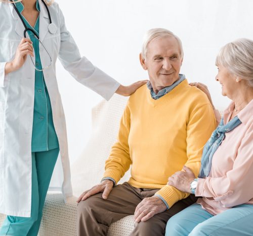 female doctor standing near senior patients in clinic