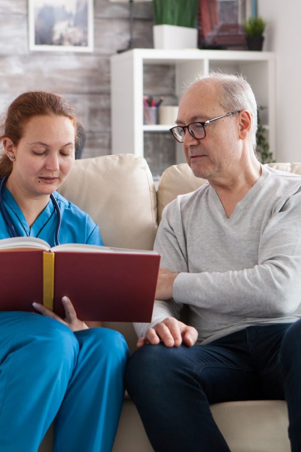 Young female doctor reading a book for old man